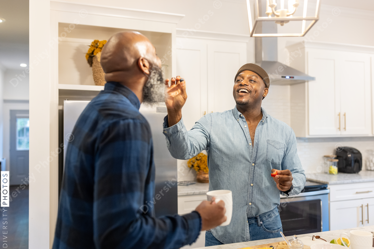 Black gay couple in kitchen at home, playful moment, conversations
