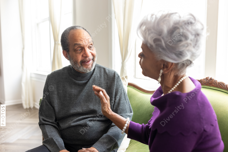 Senior couple sitting at home on sofa, conversations