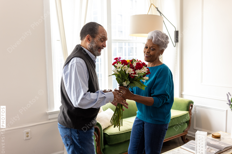 Senior couple celebrating wedding anniversary with roses at home, love connection