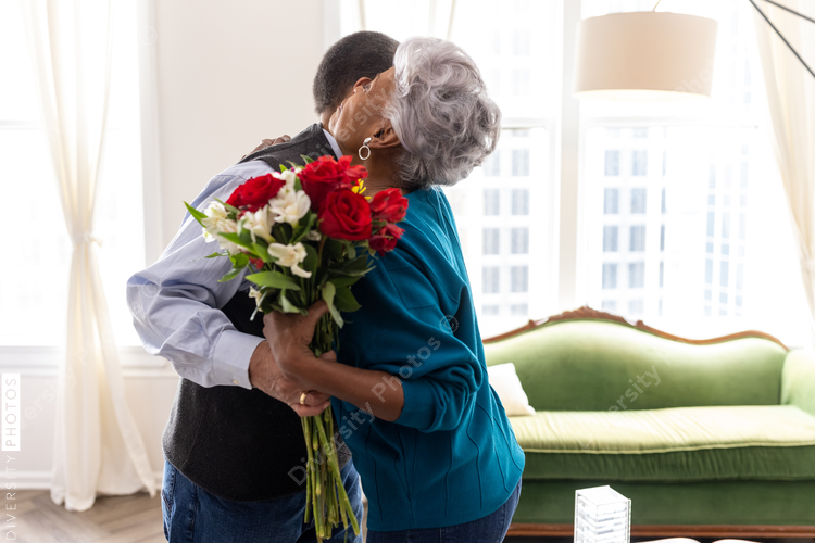 Senior couple celebrating wedding anniversary with roses at home, love connection