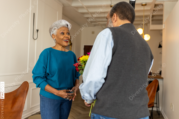 Senior couple celebrating wedding anniversary with roses at home, love connection