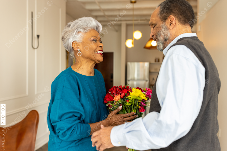 Senior couple celebrating wedding anniversary with roses at home, love connection
