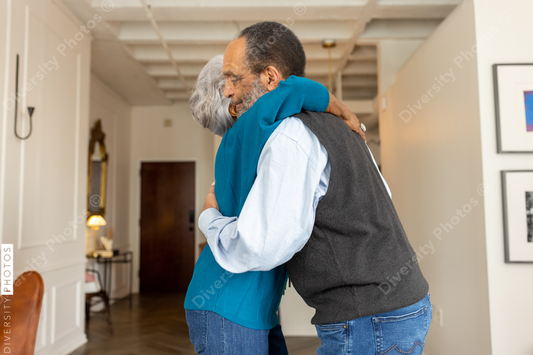 Black senior couple embracing, celebrating their love with rose flowers at home