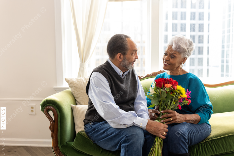 Senior African American couple sitting, smiling, on couch, connections