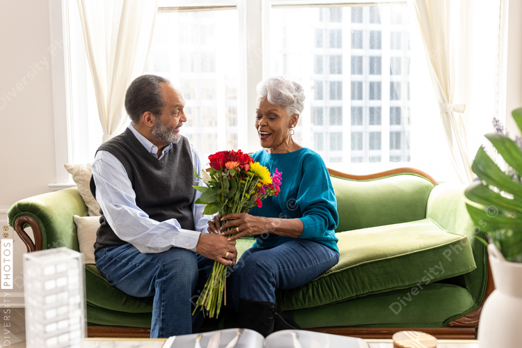 Senior African American couple sitting, smiling, on couch, connections