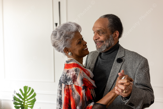 Black senior couple slow dancing at home in living room, formal wear, anniversary