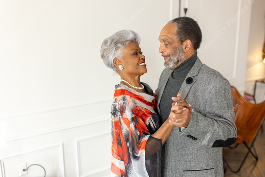 Black senior couple slow dancing at home in living room, formal wear, anniversary