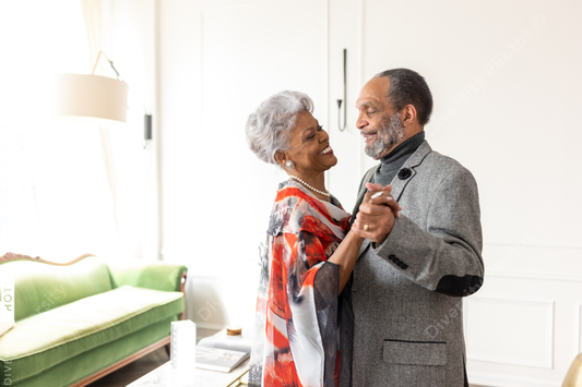 Black senior couple slow dancing at home in living room, formal wear, anniversary