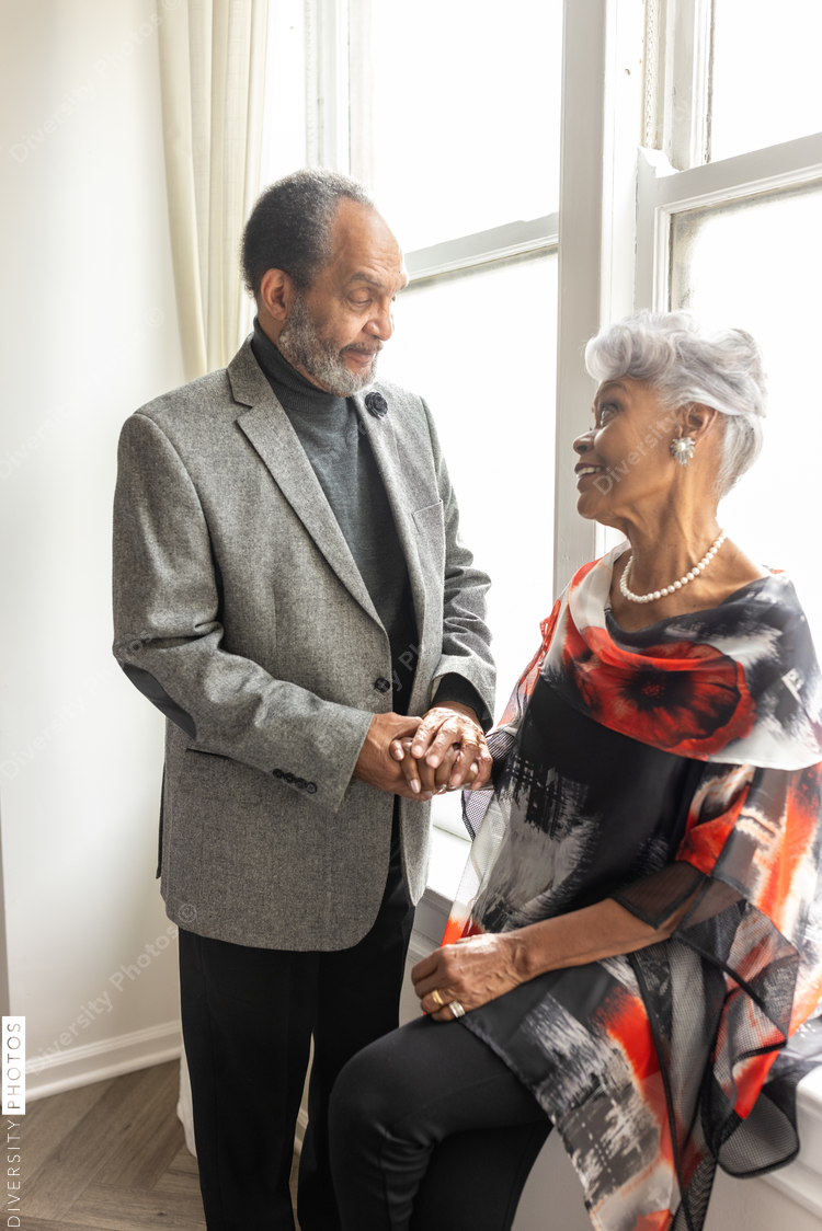 Senior couple holding hands at home